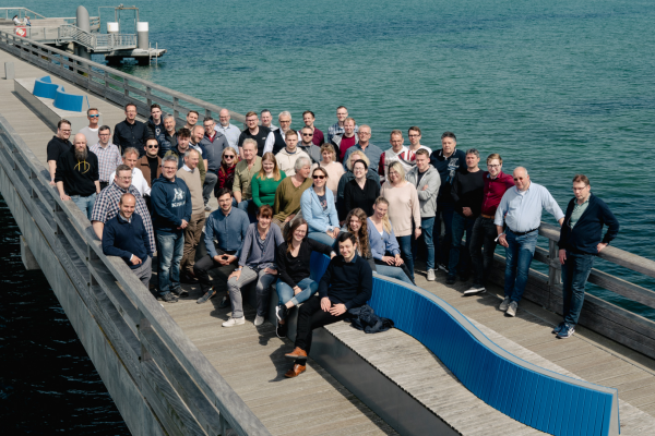 Ein Gruppenfoto aller Microsoft-ExpertInnen der akquinet NEXT GmbH auf einem Steg an der Ostsee bei strahlendem Sonnenschein während der jährlichen Strategietagung.