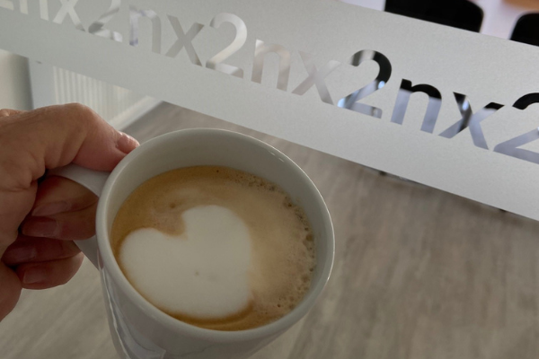 Ein warmer, leckerer Kaffee mit Herz-Milchschaum vorm Meetingraum der akquinet nx2 GmbH.